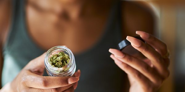 A person holding a jar of marijuana
