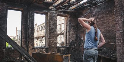 Woman standing in a burned down home