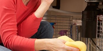 A person kneeling and holding a sponge